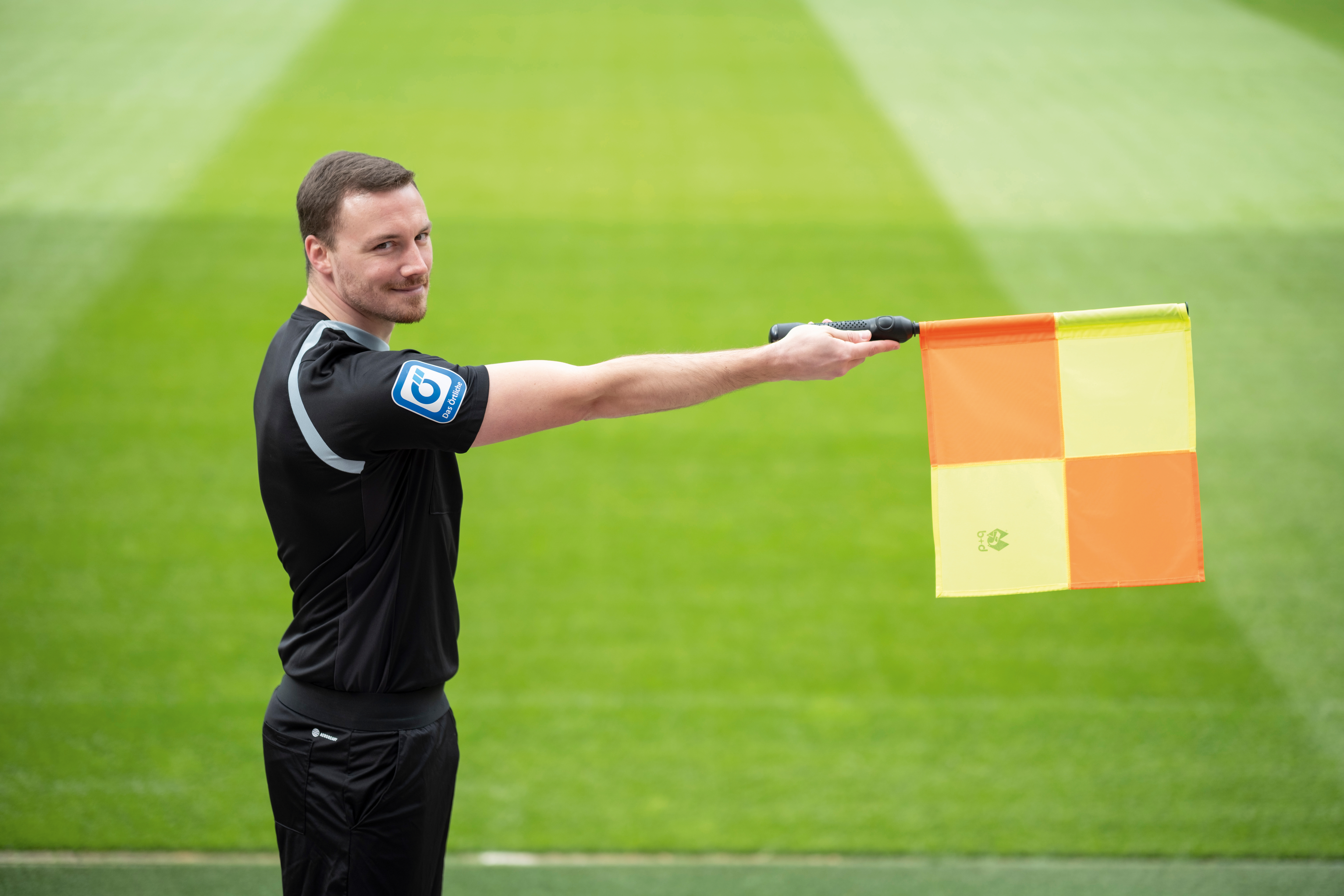  Schiedsrichterassistent Philipp Hüwe hebt auf einem Fußballfeld eine Fahne.