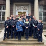 Polizeipräsidentin Friederike Zurhausen mit jungen Polizeibeschäftigten vor dem Haupteingang der Villa ten Hompel in Münster