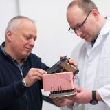 Felix Baum (links) und Mathias Teroerde befestigen eine Pistole in einem passend geformten Schaumstoffteil, damit die Waffe von allen Seiten durchleuchtet werden kann.