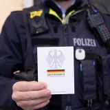 Ein Polizeibeamter hält eine Ausgabe des Grundgesetzes in den Händen.