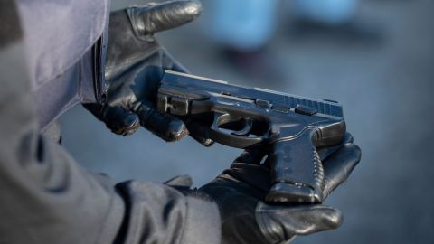 A police officer holds a semblance of a weapon in his gloved hands.