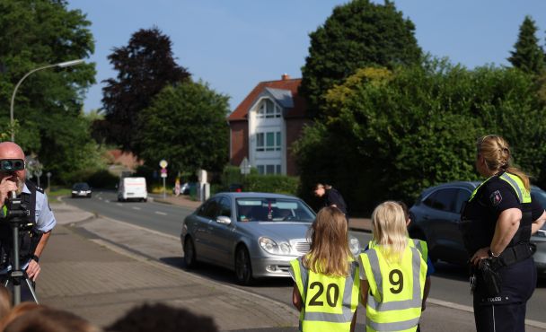 Kinder kontrollieren zusammen mit einer Polizisten einen Autofahrer