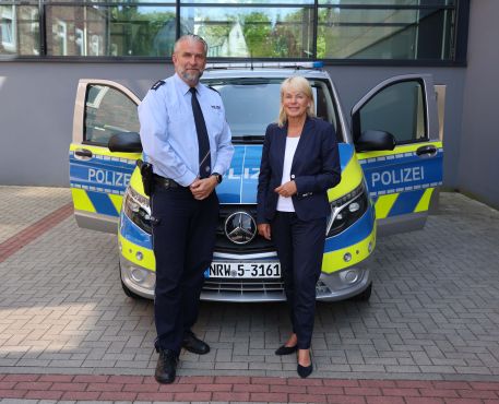 Markus Häbel und Polizeipräsidentin Friederike Zurhausen stehen vor einem Streifenwagen